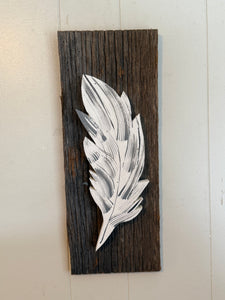 Single feather on barn board backing .
