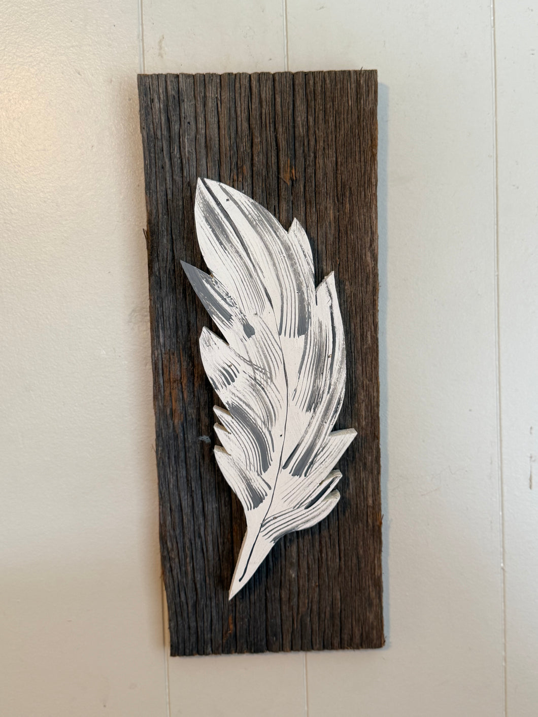 Single feather on barn board backing .